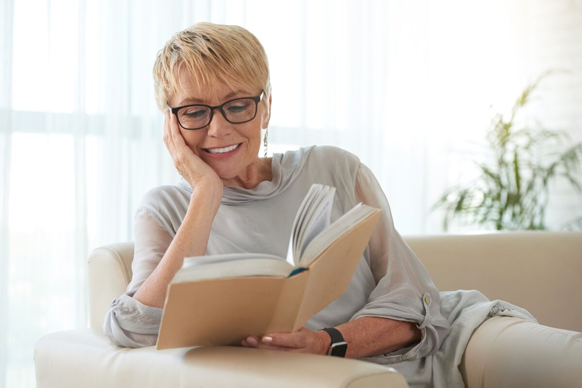 A woman reads a book on a sofa